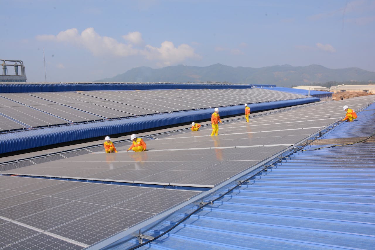 Workers installing solar panels on a large roof, highlighting renewable energy and sustainability.